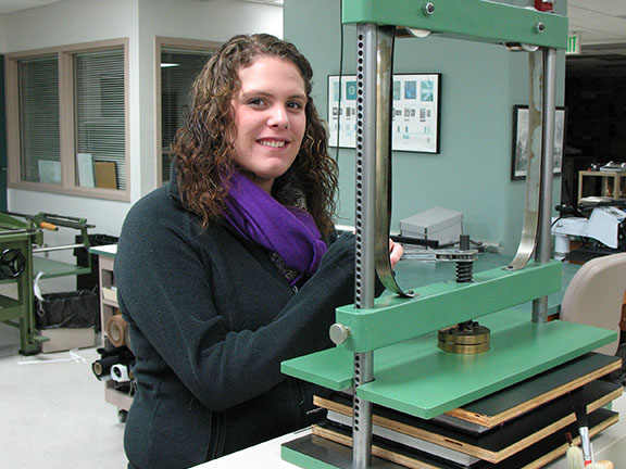 Ashley clamps down adhesive bindings in a book press.