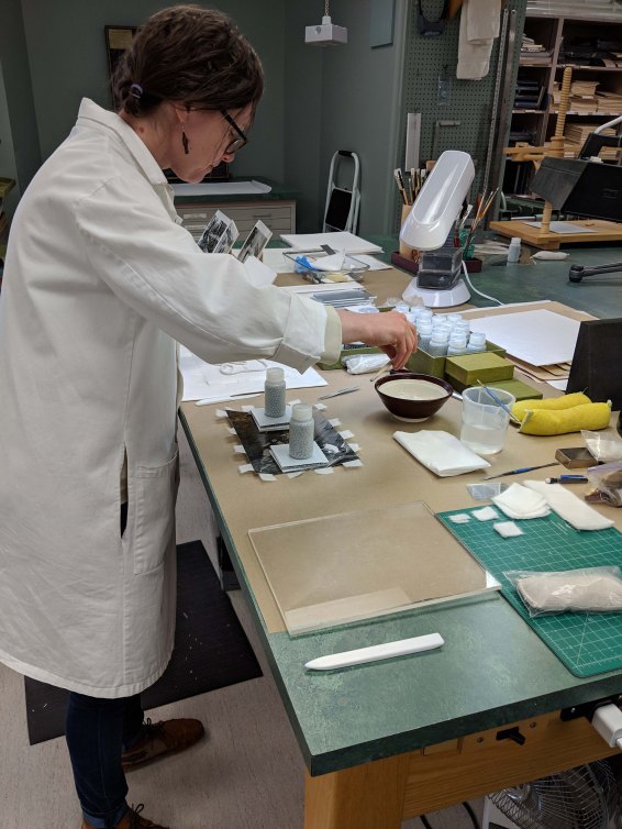 Collections conservator Sonya Barron working on attaching tissue hinges to a photo.